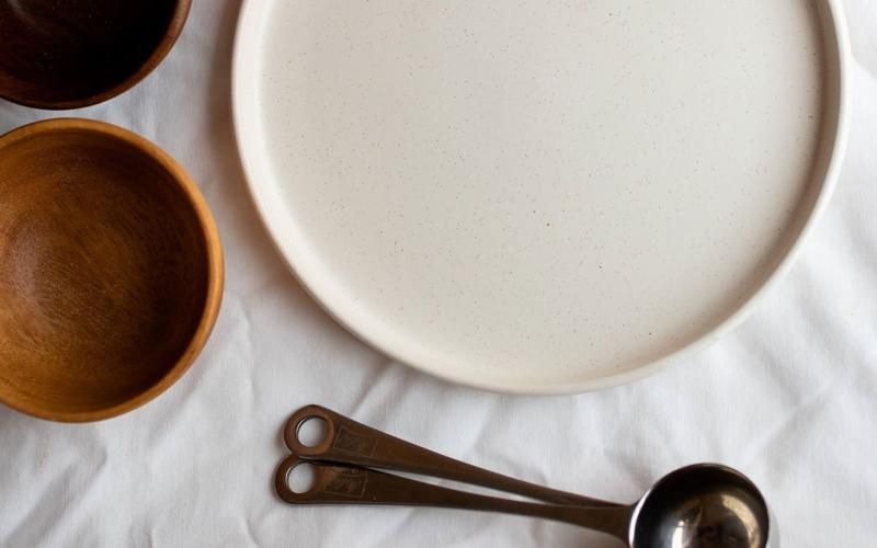 bowls, a plate and measuring spoons arranged neatly on cloth