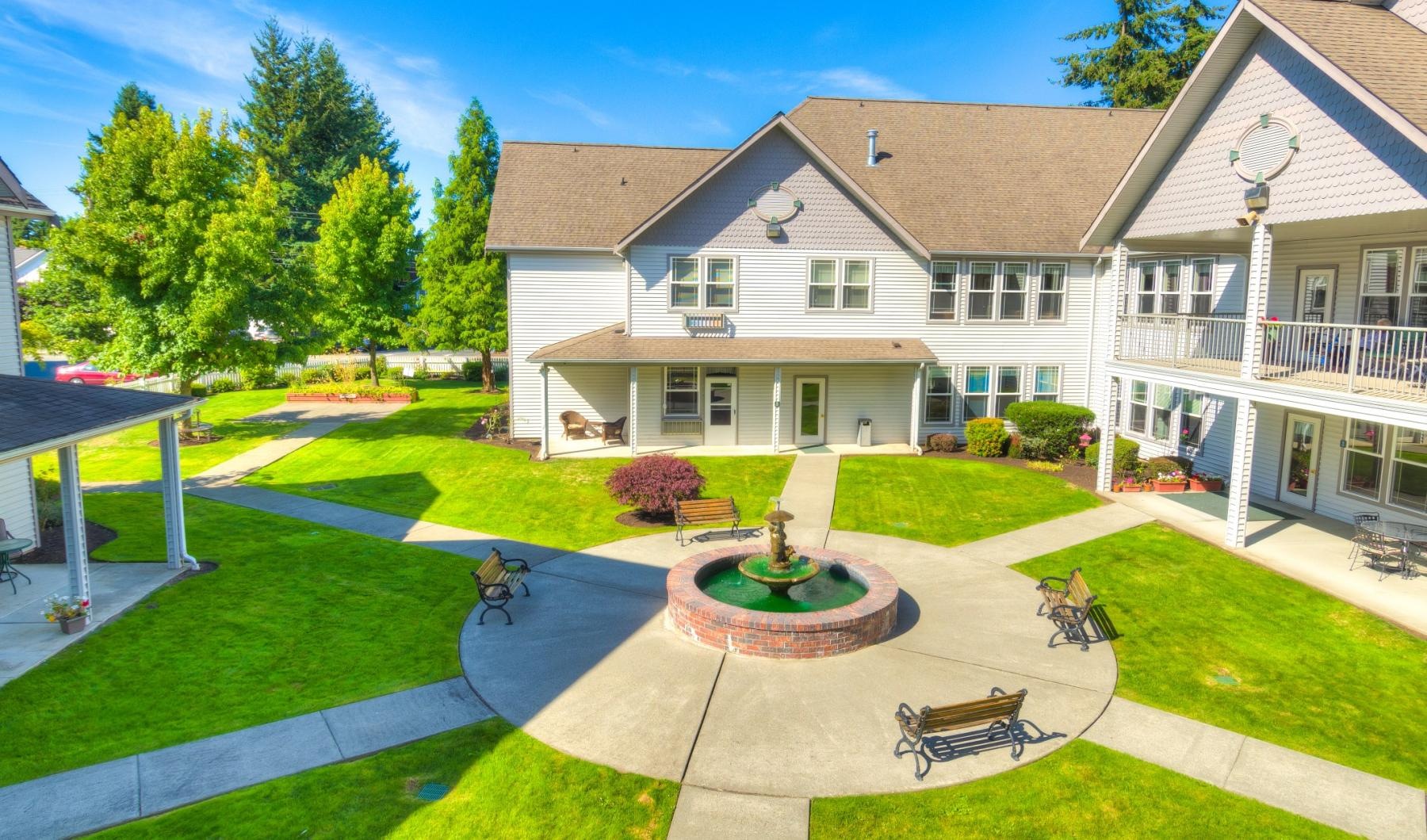 a large house with a fountain and benches