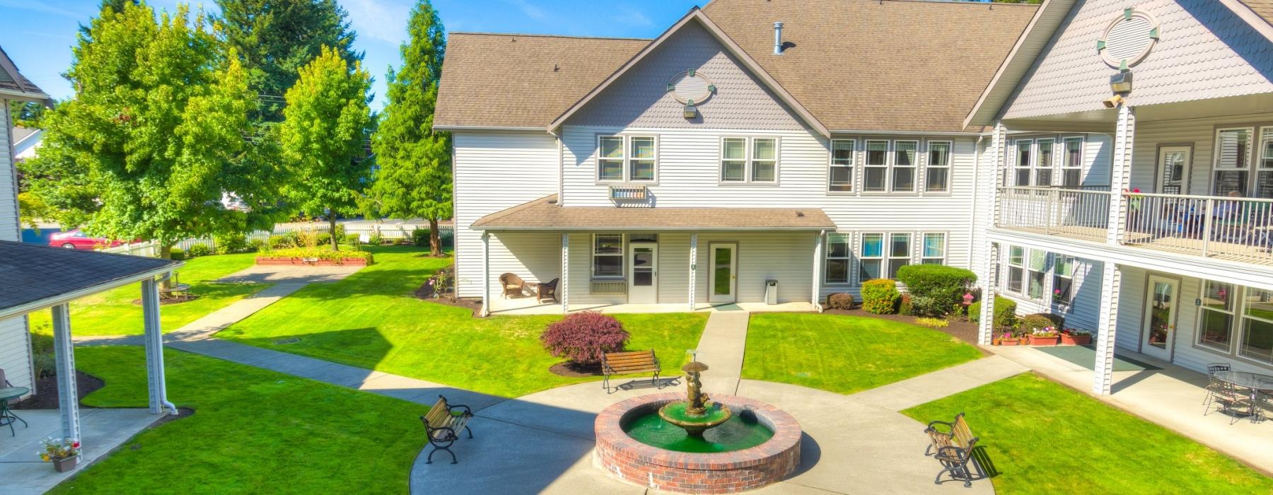 a large house with a fountain and benches